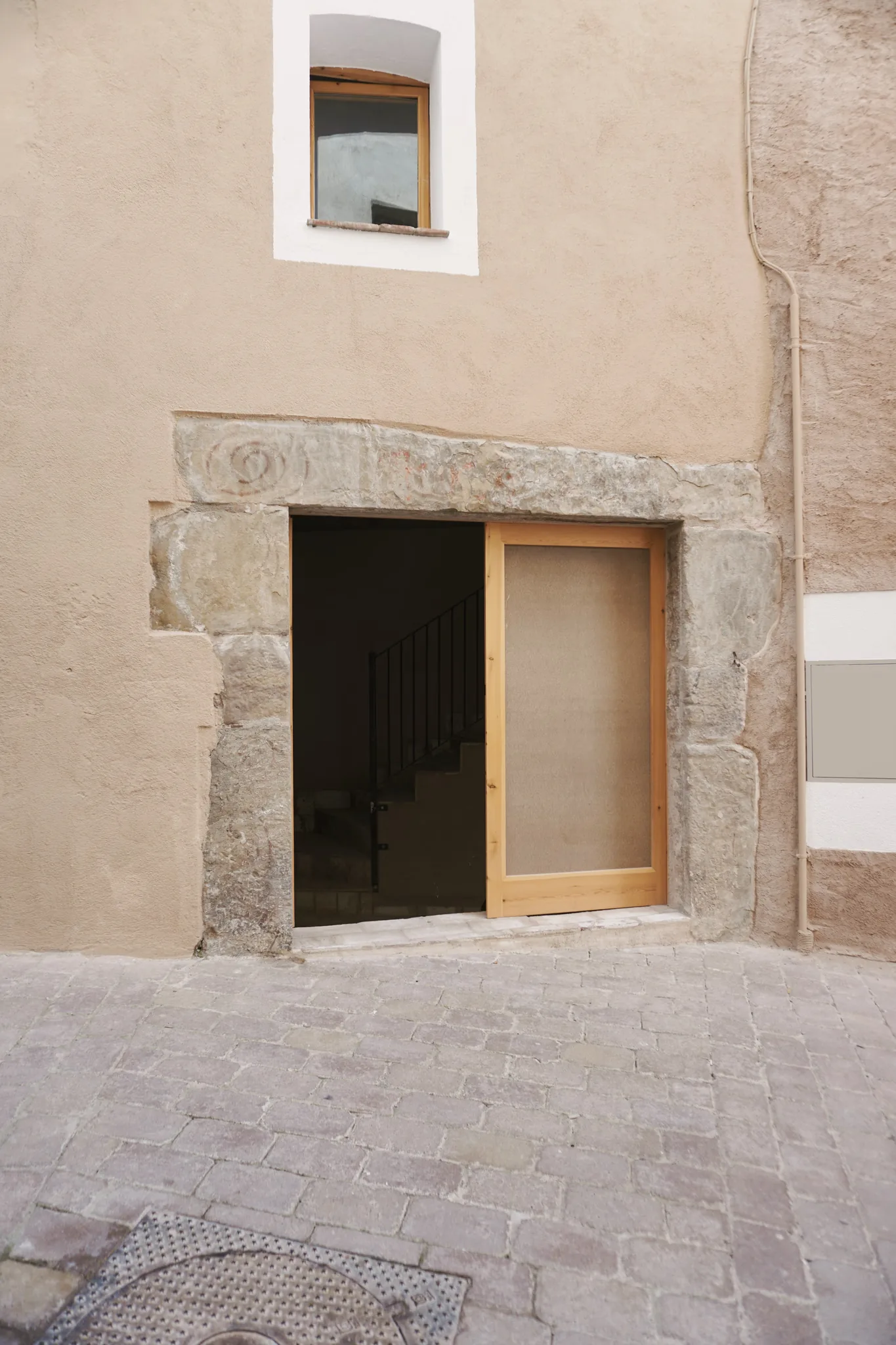 Dintel de piedra original tallada en la entrada de la reforma de una casa de esquina en Sant Llorenç Savall
