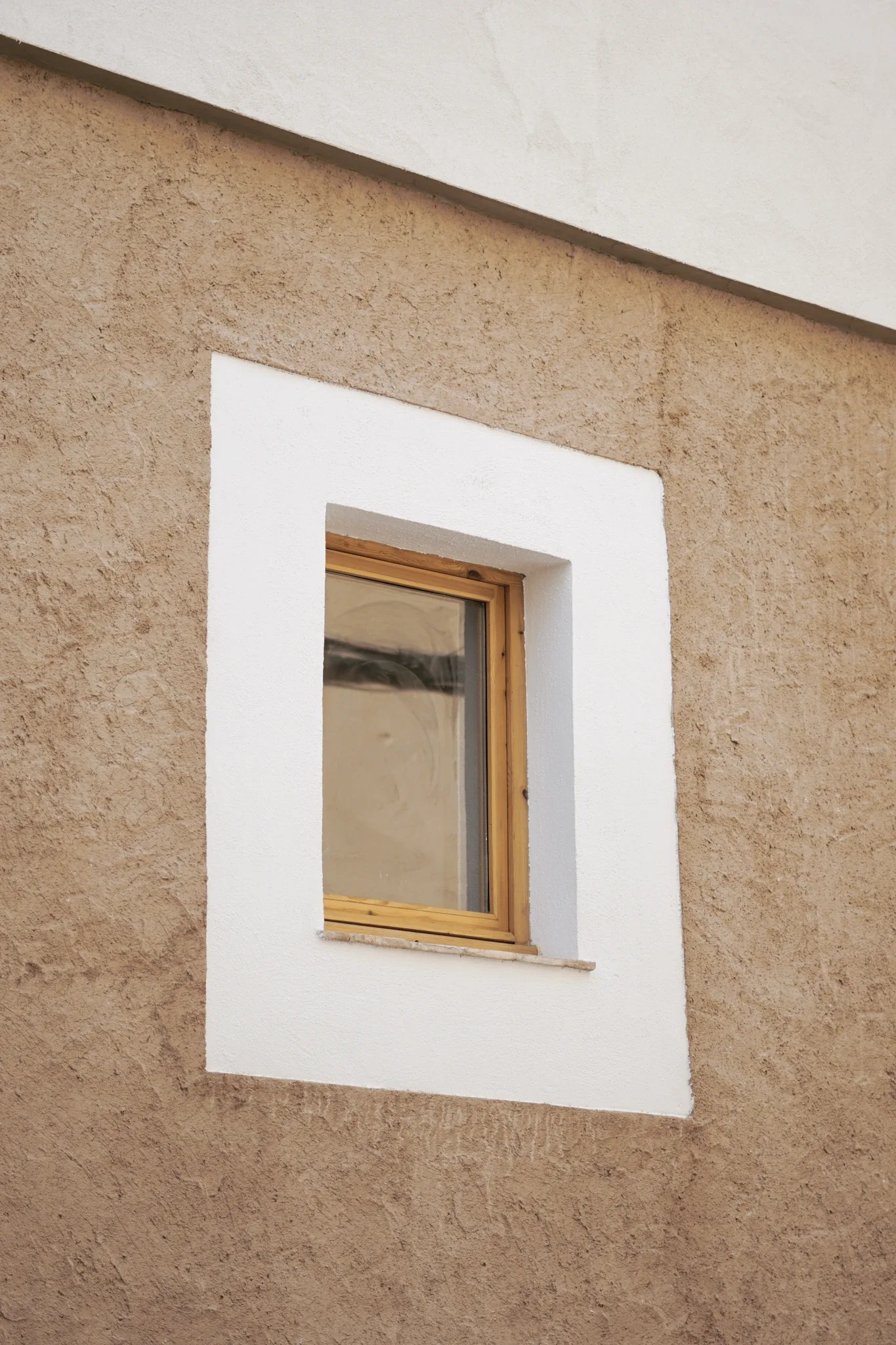 Ventana de madera de pino en la fachada ocre de la reforma en Sant Llorenç Savall
