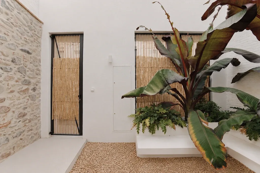 Patio interior con muro de piedra original, reforma integral de vivienda en Granollers, Barcelona